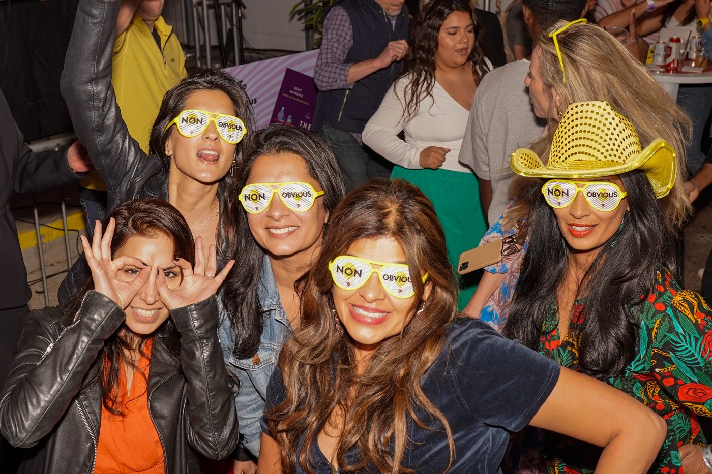 Friends in yellow Non-Obvious glasses at a live experience